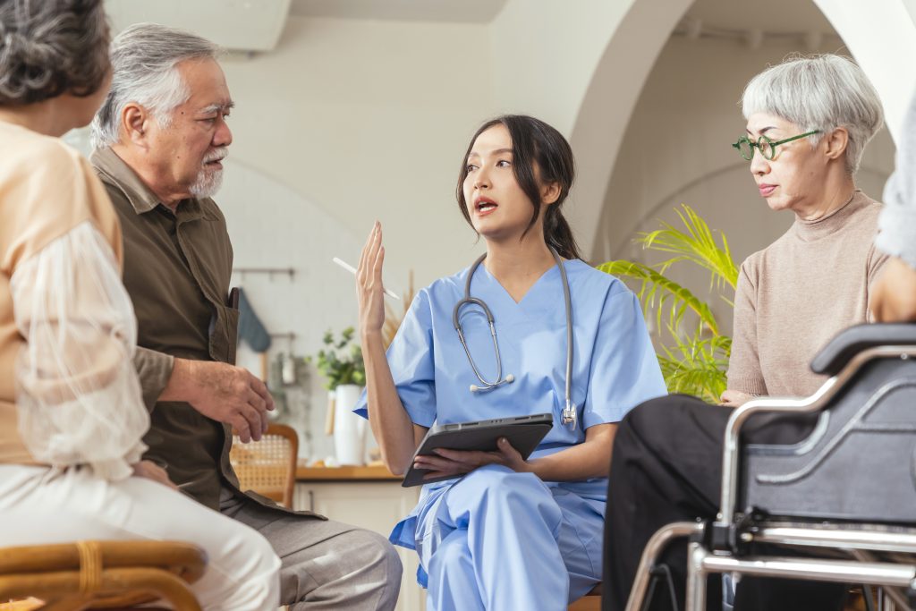 Caretakers with senior couple sitting in living room at nursing home